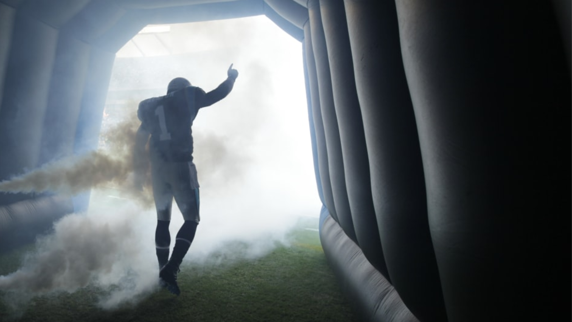 Football player walking through smoke toward the field